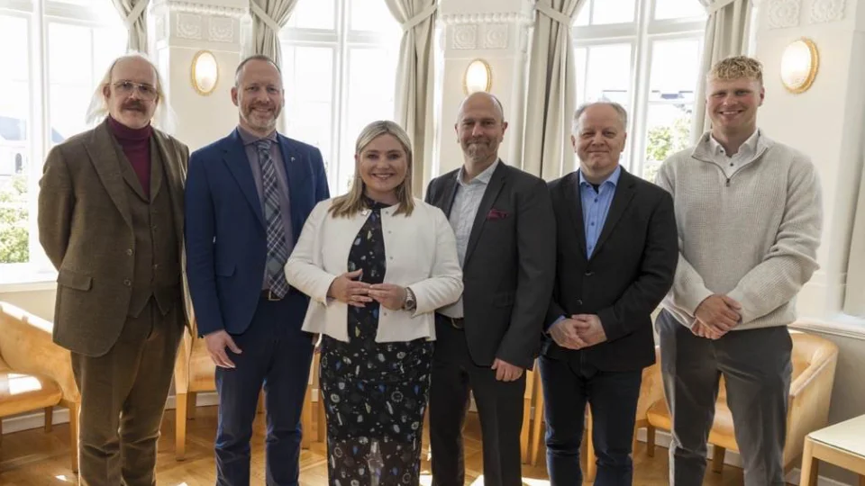 RUV Orð: Nytt verktøy for å lære islandsk for innvandrere lansert Gruppebillede af seks personer i formel påklædning, stående foran vinduer i et lyst rum.