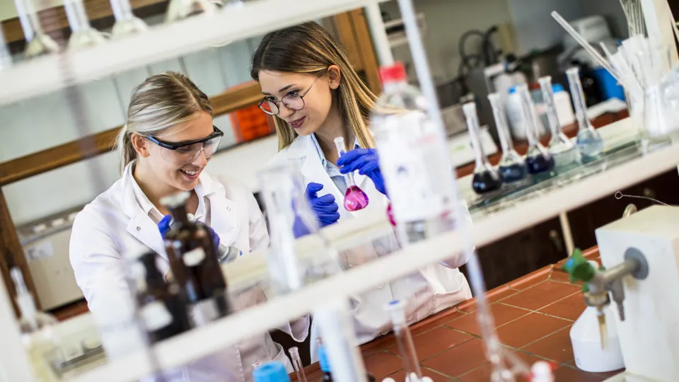 Sverige tar fram en STEM-strategi Två unga kvinnliga forskare i laboratorieutrustning arbetar med kemiska lösningar i ett laboratorium.