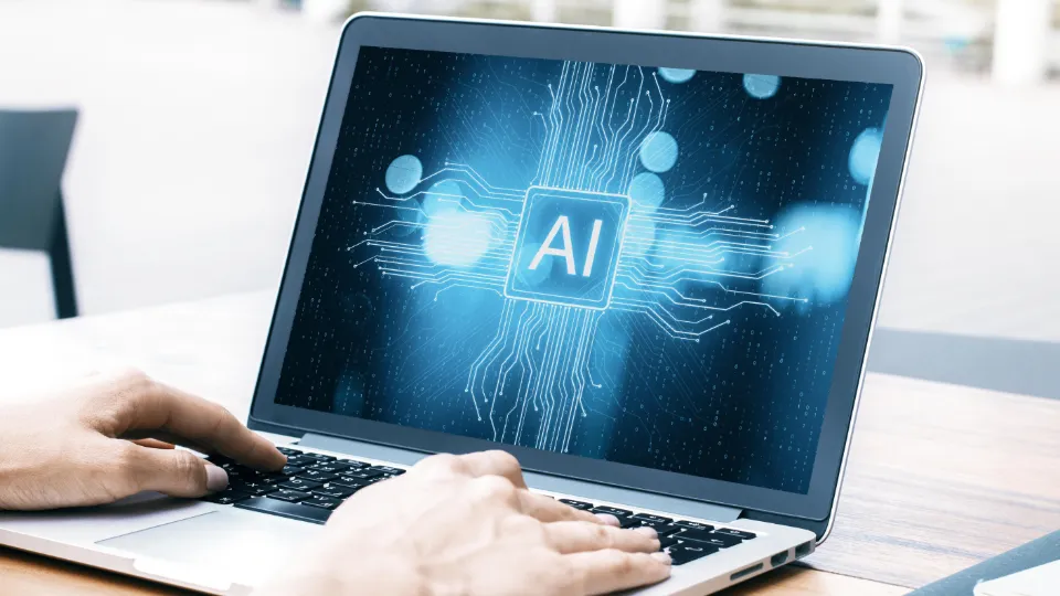 Fem nye filmer om artificial intelligence (AI) og arbeidsliv Person som bruker en bærbar datamaskin med et digitalt AI-symbol på skjermen.