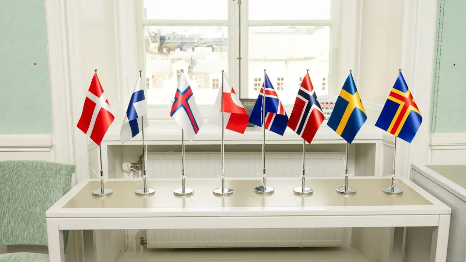 Gevinsten med validering: Økonomisk og samfundsmæssigt perspektiv Små nordiske bordflag på en hvidt bord foran et vindue.
