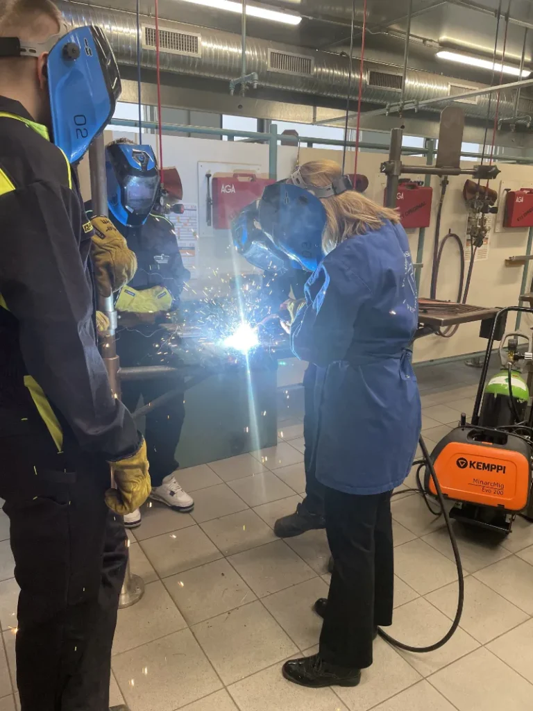 Sveiseopplæring ved FÍV skole på Island, der elever bruker sveiseskjerm og verneutstyr mens de sveiser metall i verkstedet.